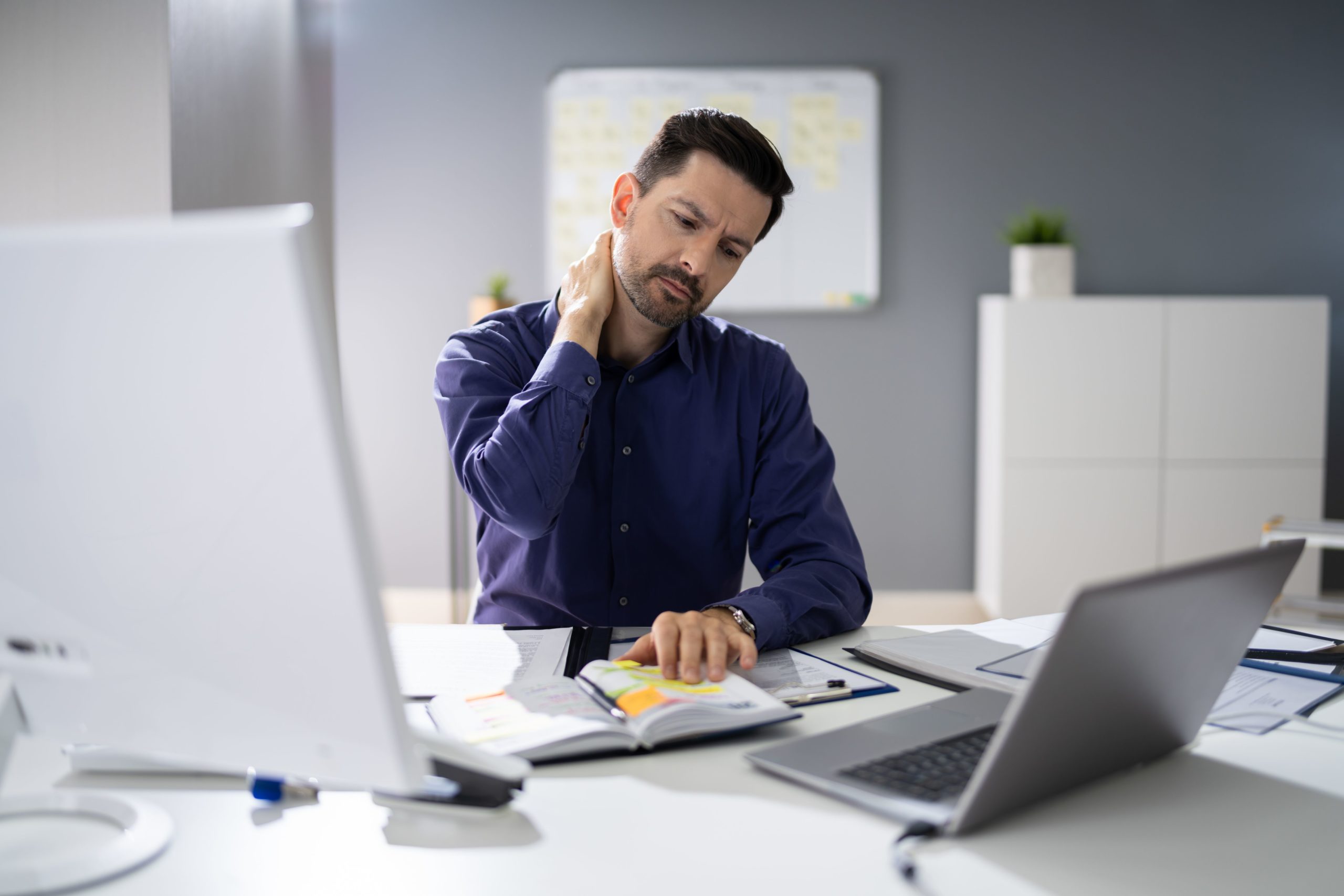 Male Businessman Suffering From Neck Pain At His Desk